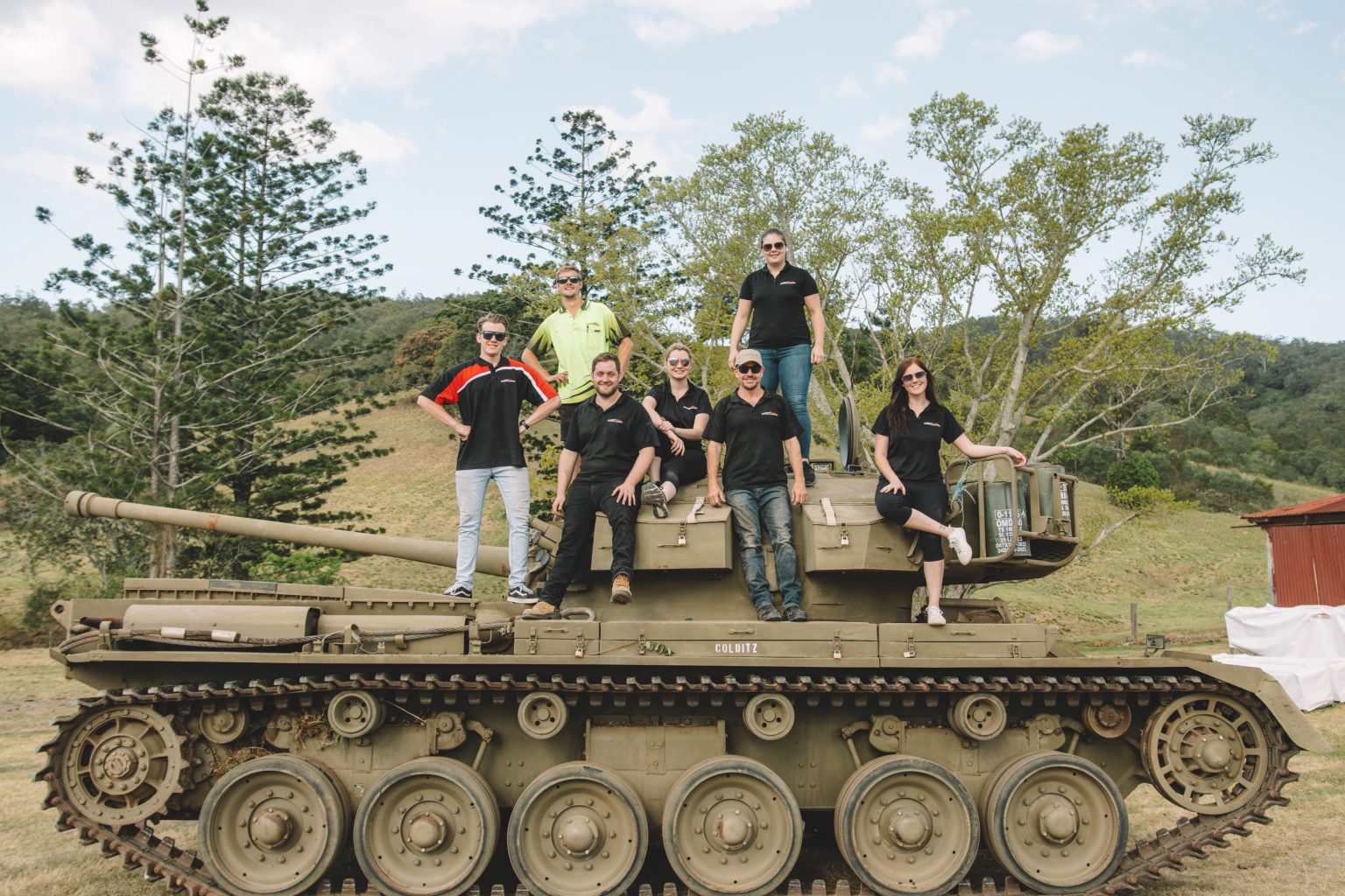 7 person giving pose to the picture standing on the fight weapon vehicles